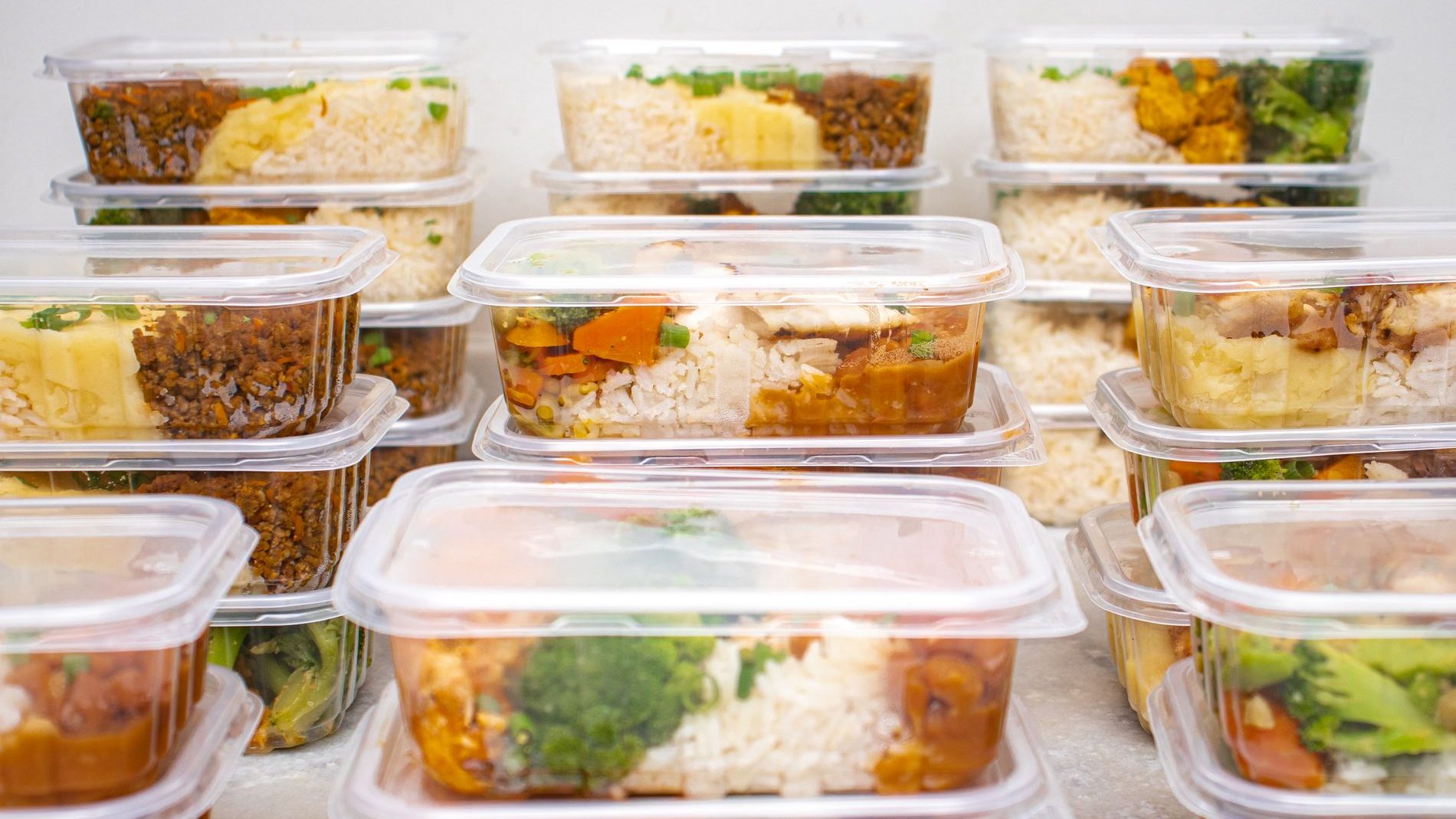 Envases plásticos transparentes con tapa, apilados y llenos de comida preparada