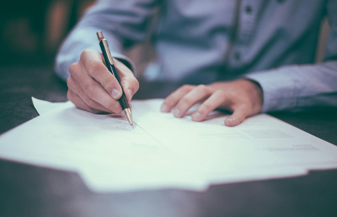 Manos firmando un documento sobre un escritorio