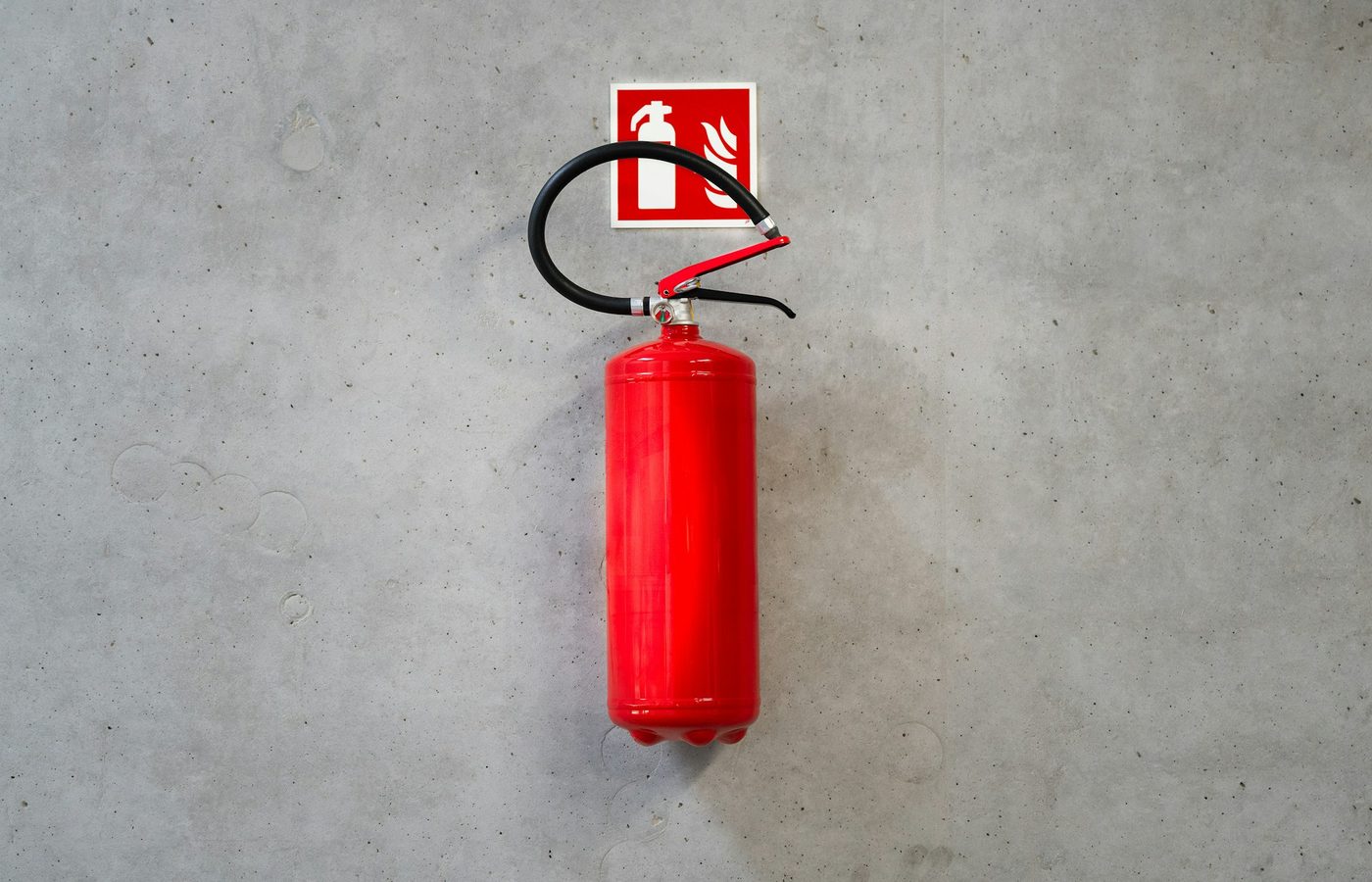 Extintor rojo instalado en un muro de concreto