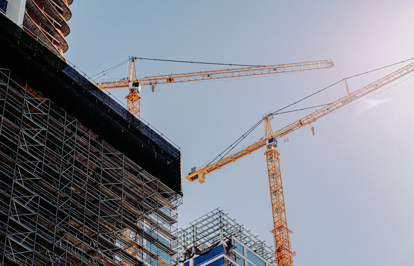 Grúas torre amarillas junto a andamios de un edificio en construcción