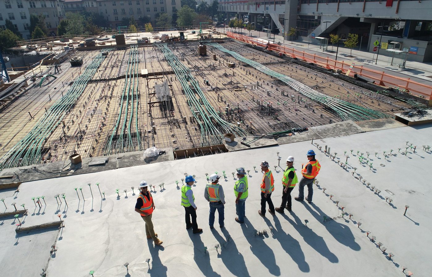 Grupo de trabajadores con casco y chaleco reflectante en una obra vista desde arriba